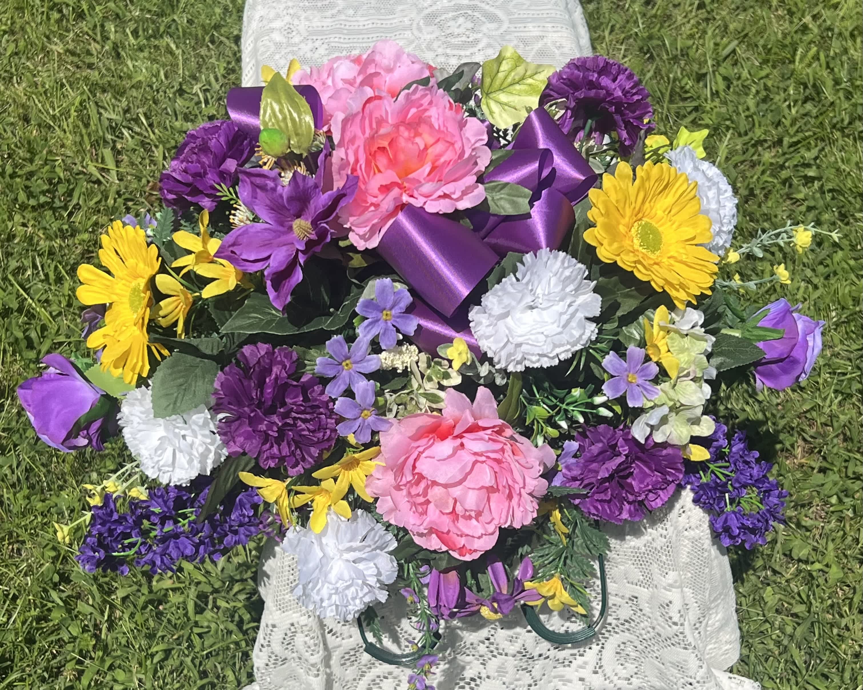 Colorful bouquet with pink, purple, yellow, and white flowers tied with a purple ribbon