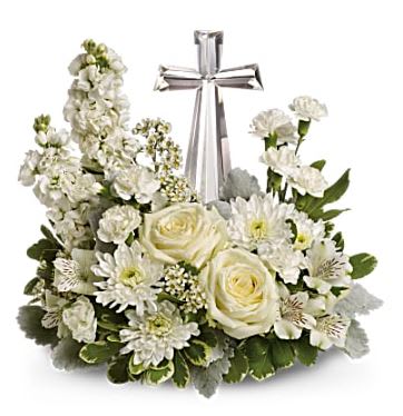 White floral arrangement with roses and daisies around a silver cross