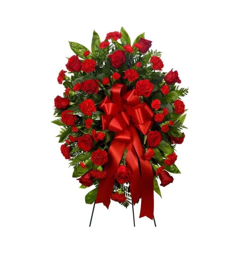 Mixed Red Florals Standing Spray - A standing spray of red roses and red carnations on a bed of greens. Displayed on a 4.5ft easel.