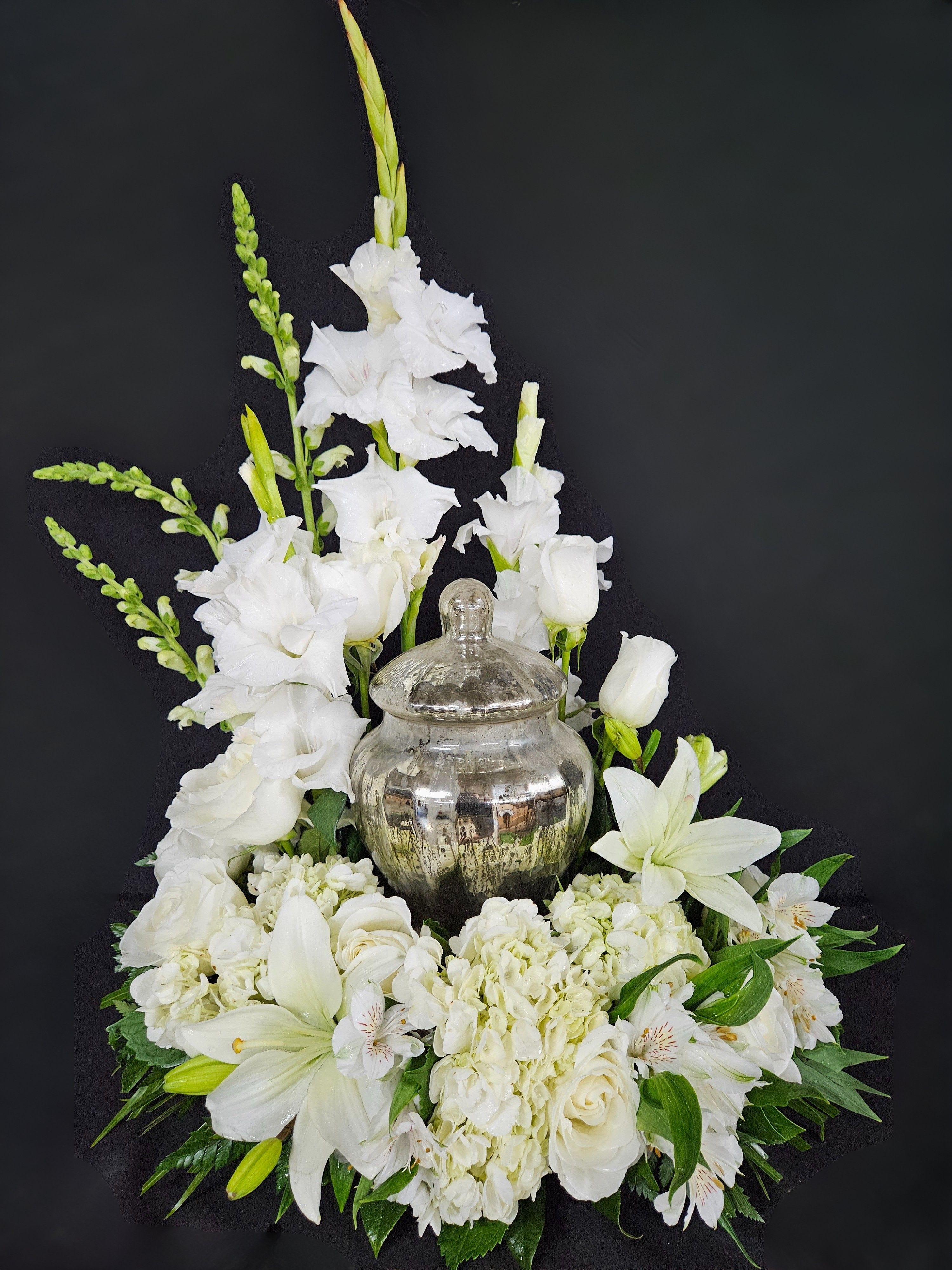 Eternal Peace Urn Design - Reminisce and cherish the life of a lost loved one with the Eternal Peace cremation arrangement that encompasses the urn of your choice. This classy arrangement features heavenly white hues with lavish hydrangeas, lilies, and roses, making it ideal for any memorial service. Arrangement is designed to hold a standard size urn. Urn not included.