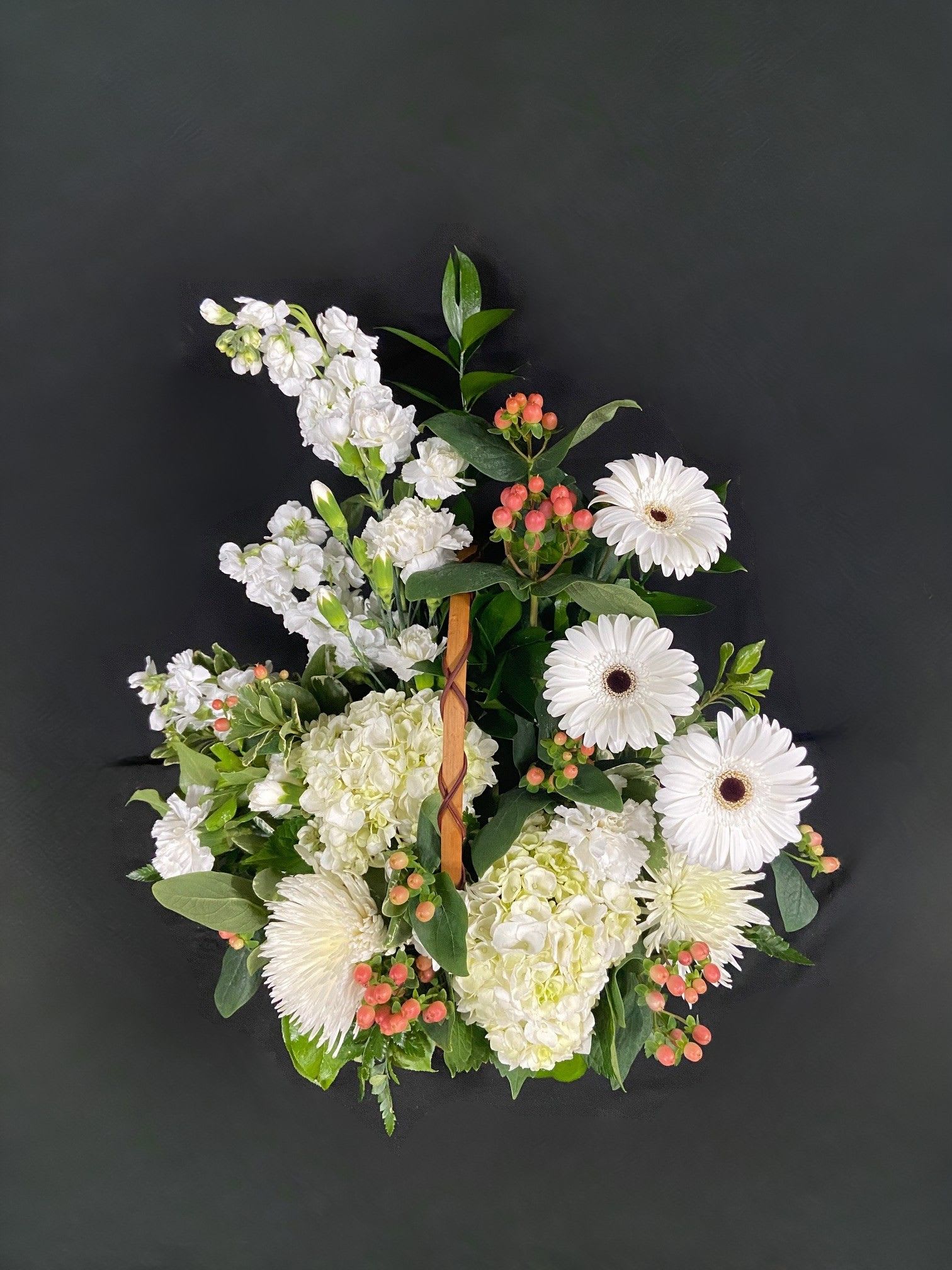 White floral wreath with gerbera daisies and hydrangeas on a dark background