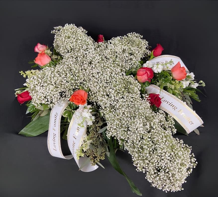 White baby's breath arrangement with red and coral roses and memorial ribbons