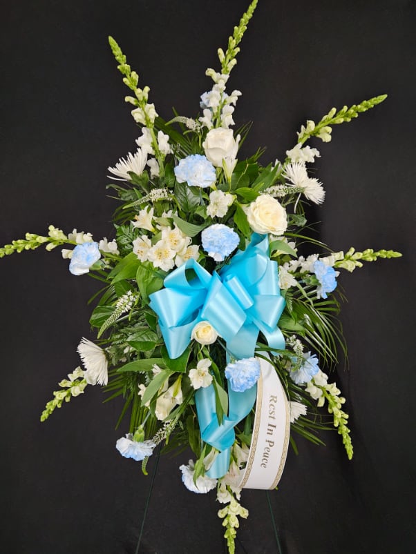 Light Blue &amp; White Standing Spray - Light blue carnations are paired with white roses, white mums, white snapdragons, and other assorted white flowers. Arrangement is mounted on a 4.5ft standing easel for prominent display at funeral services.