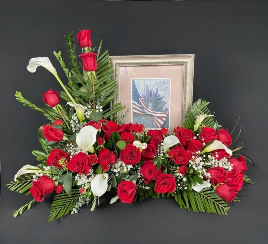Red roses and white calla lilies arranged around a framed picture.