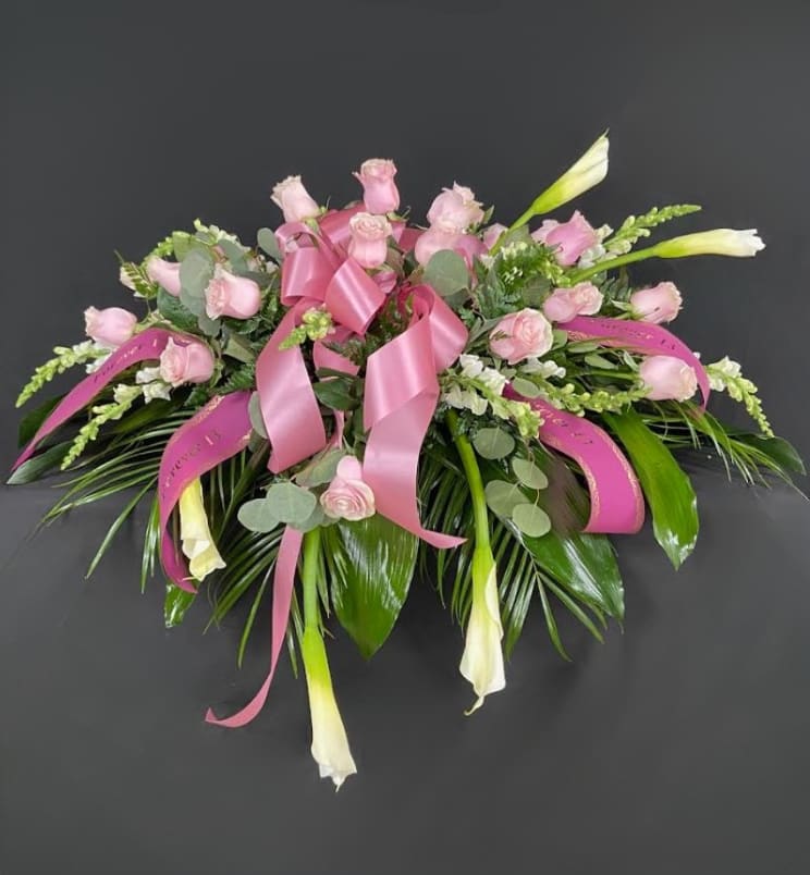 Pink rose bouquet with white calla lilies and ribbon on a dark background