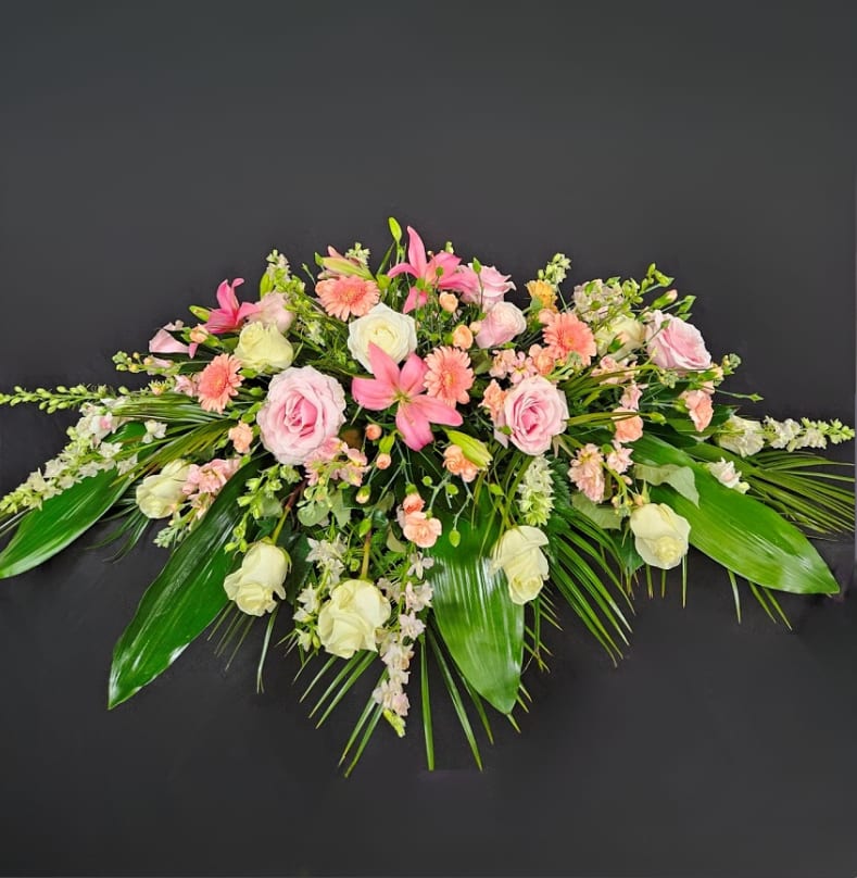 Pink and white floral spray with lilies and roses on a dark background