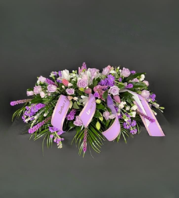 Lavender and white floral casket spray with ribbon accents