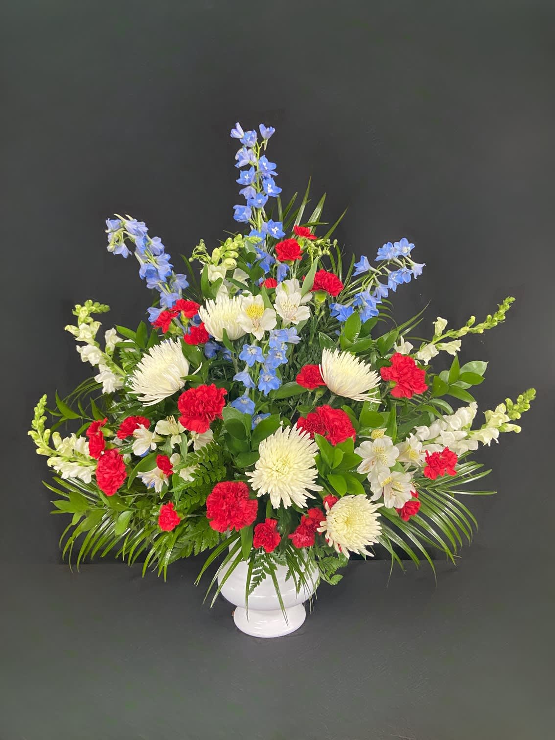 Red, white, and blue floral arrangement in a white vase