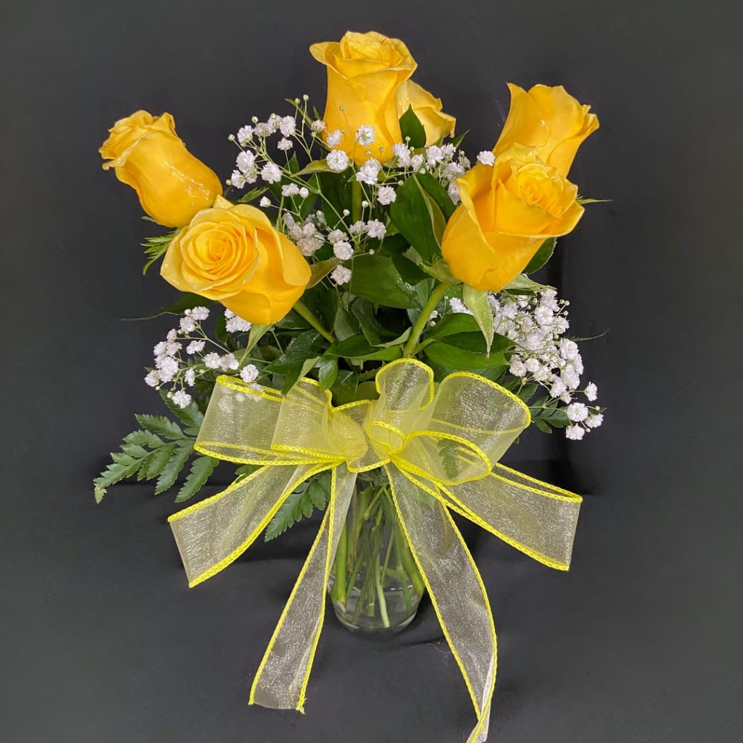 Yellow roses in a glass vase with a sheer yellow ribbon