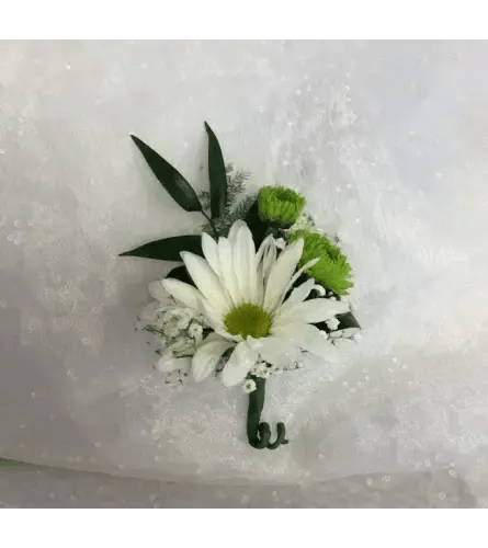 White daisy boutonniere with green accents on white fabric
