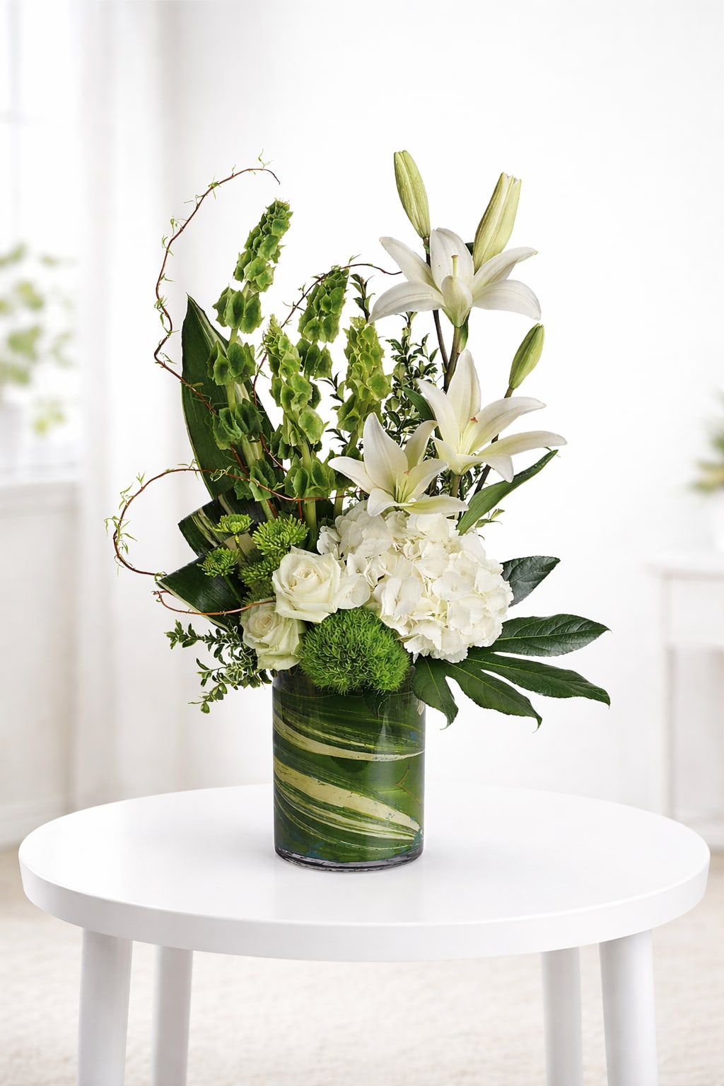 White lilies and roses arranged in a green glass vase