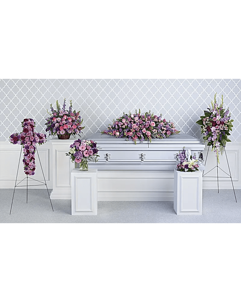 Pink and purple funeral flowers arranged around a silver casket
