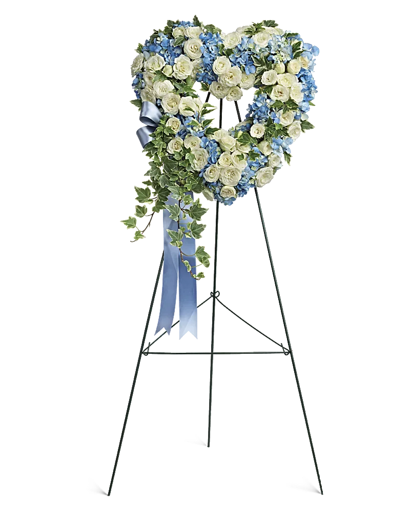Heart-shaped floral wreath on an easel with blue and white flowers
