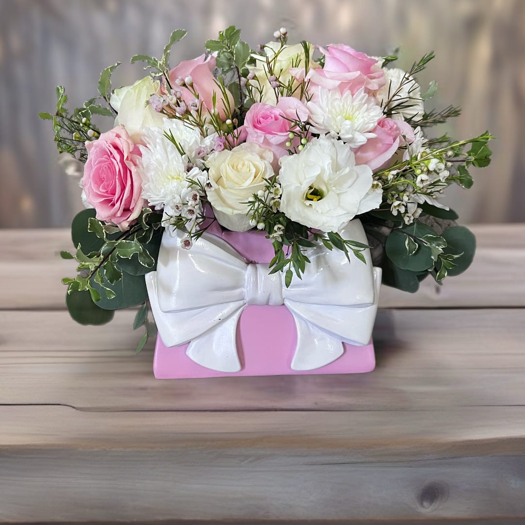 Pink and white rose arrangement in a pink box with a white bow