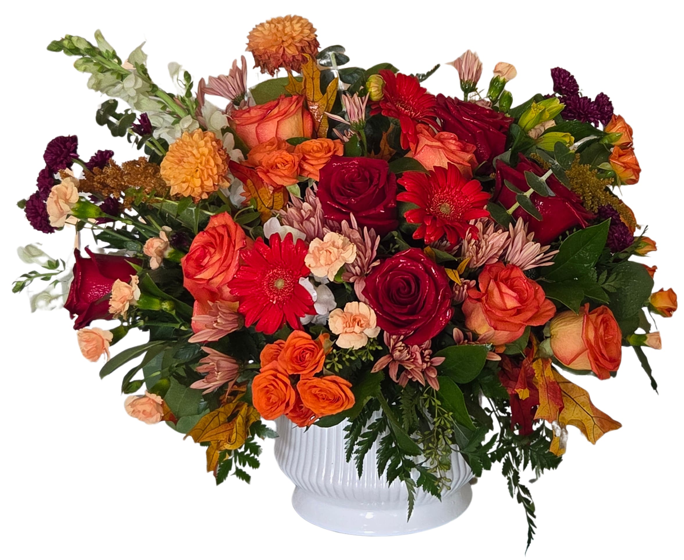 Mixed bouquet of red, orange, and peach flowers in a white vase