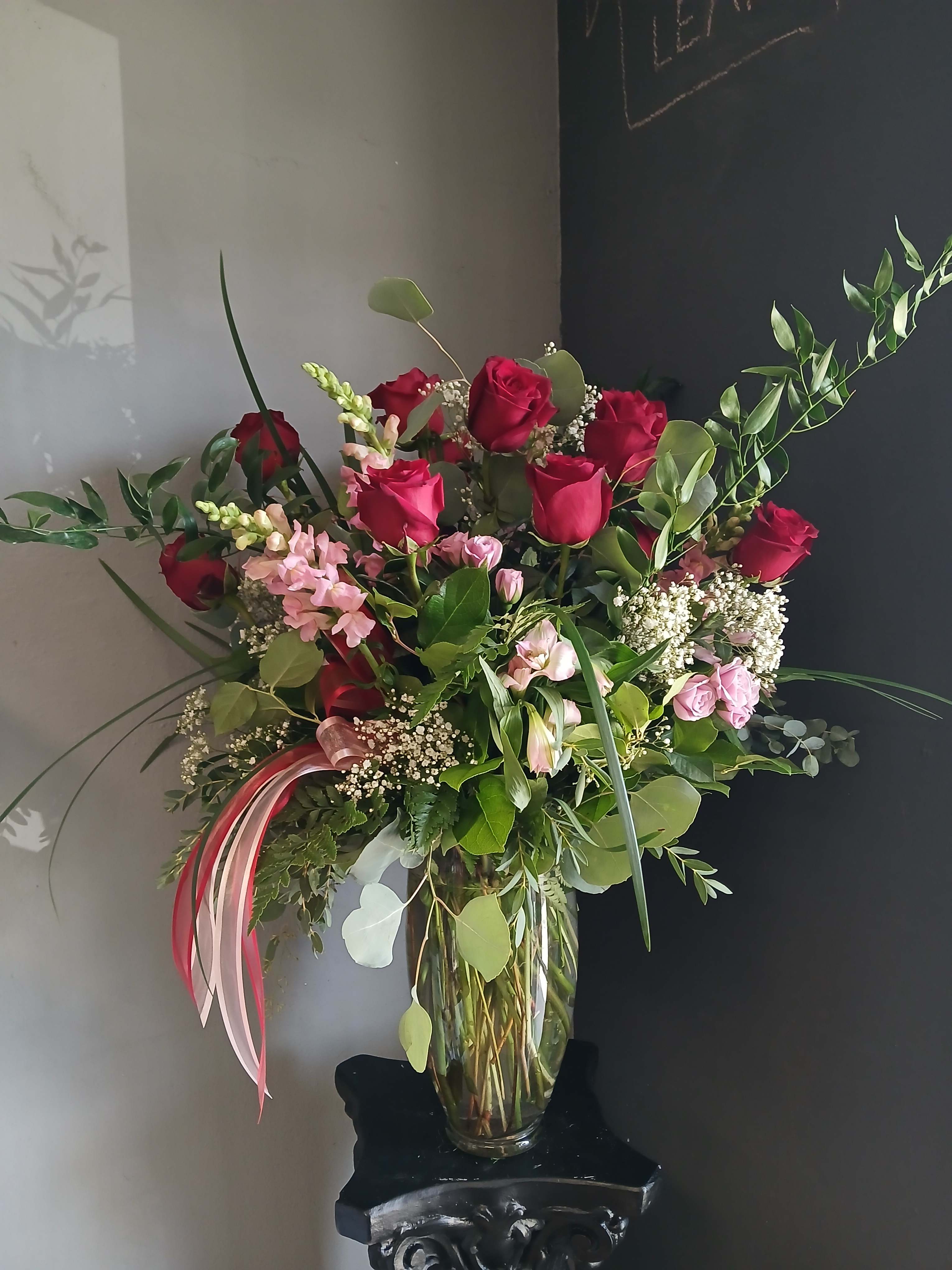 Tall bouquet of red and pink roses in a clear glass vase