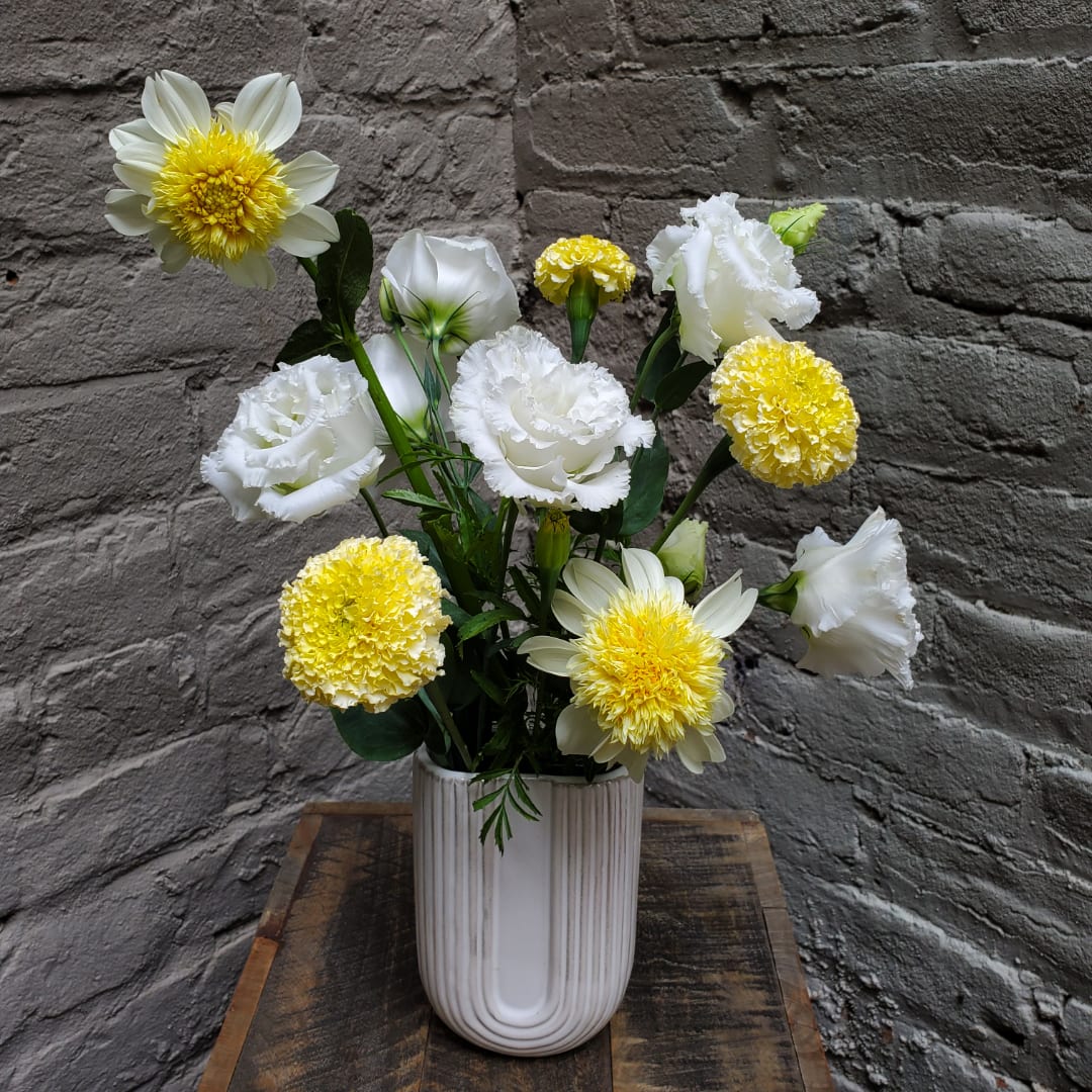 White and yellow flowers arranged in a ribbed white vase