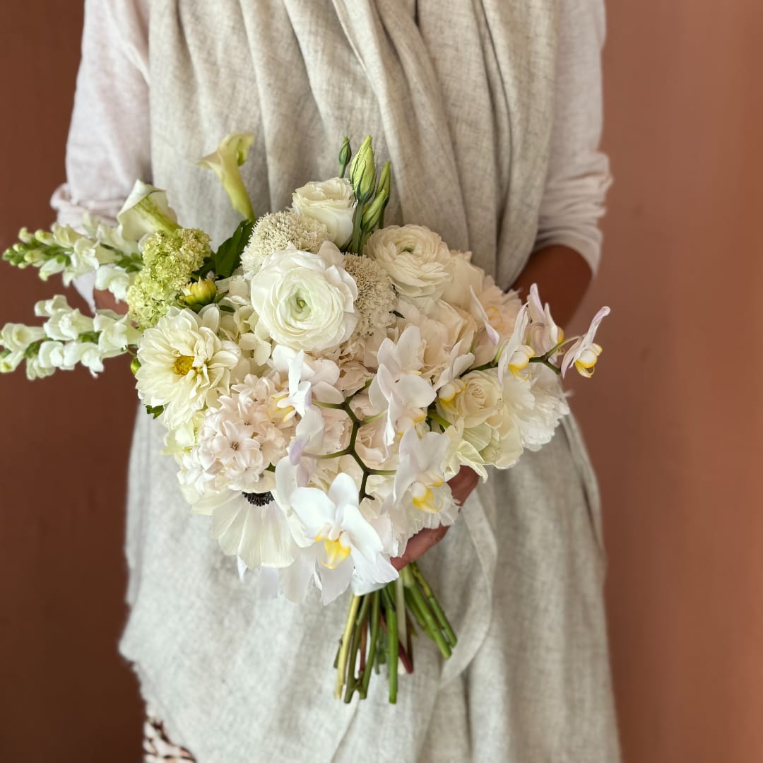 White bridal bouquet with orchids, ranunculus, and calla lilies