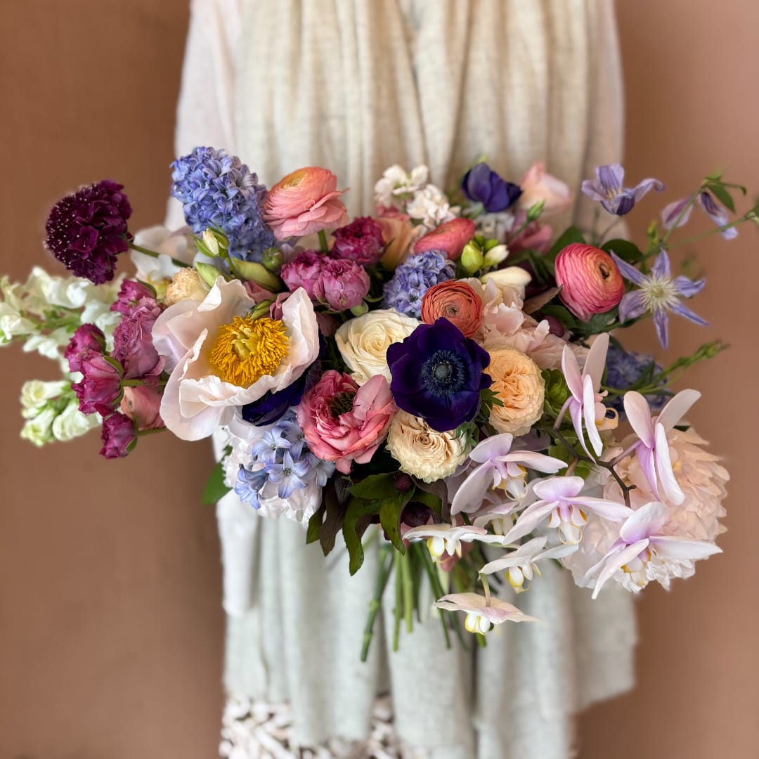 Colorful bridal bouquet with mixed blooms in pink, purple, white, and blue