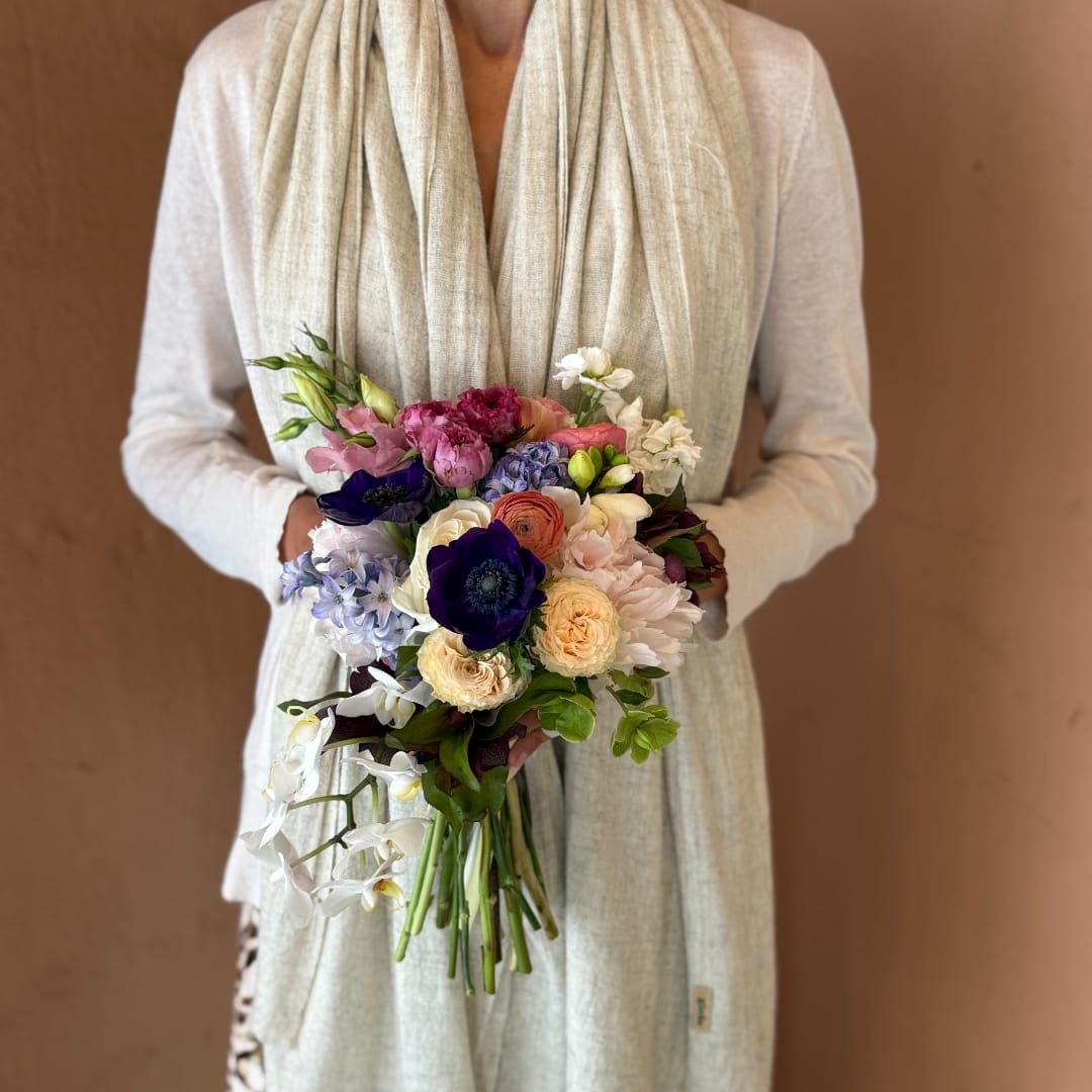 Person holding a colorful bridal bouquet with mixed flowers