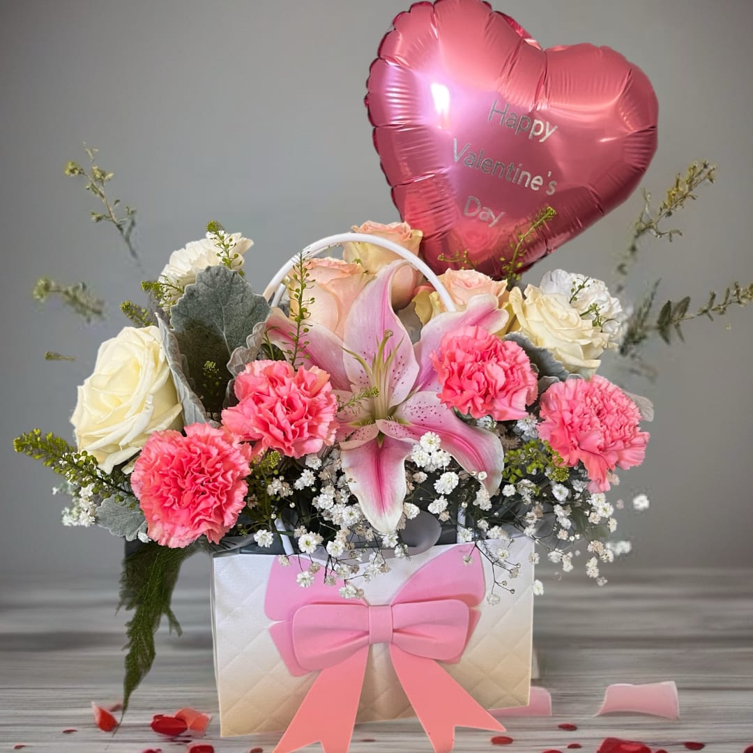 Pink heart balloon above a flower basket with roses, lilies, and carnations