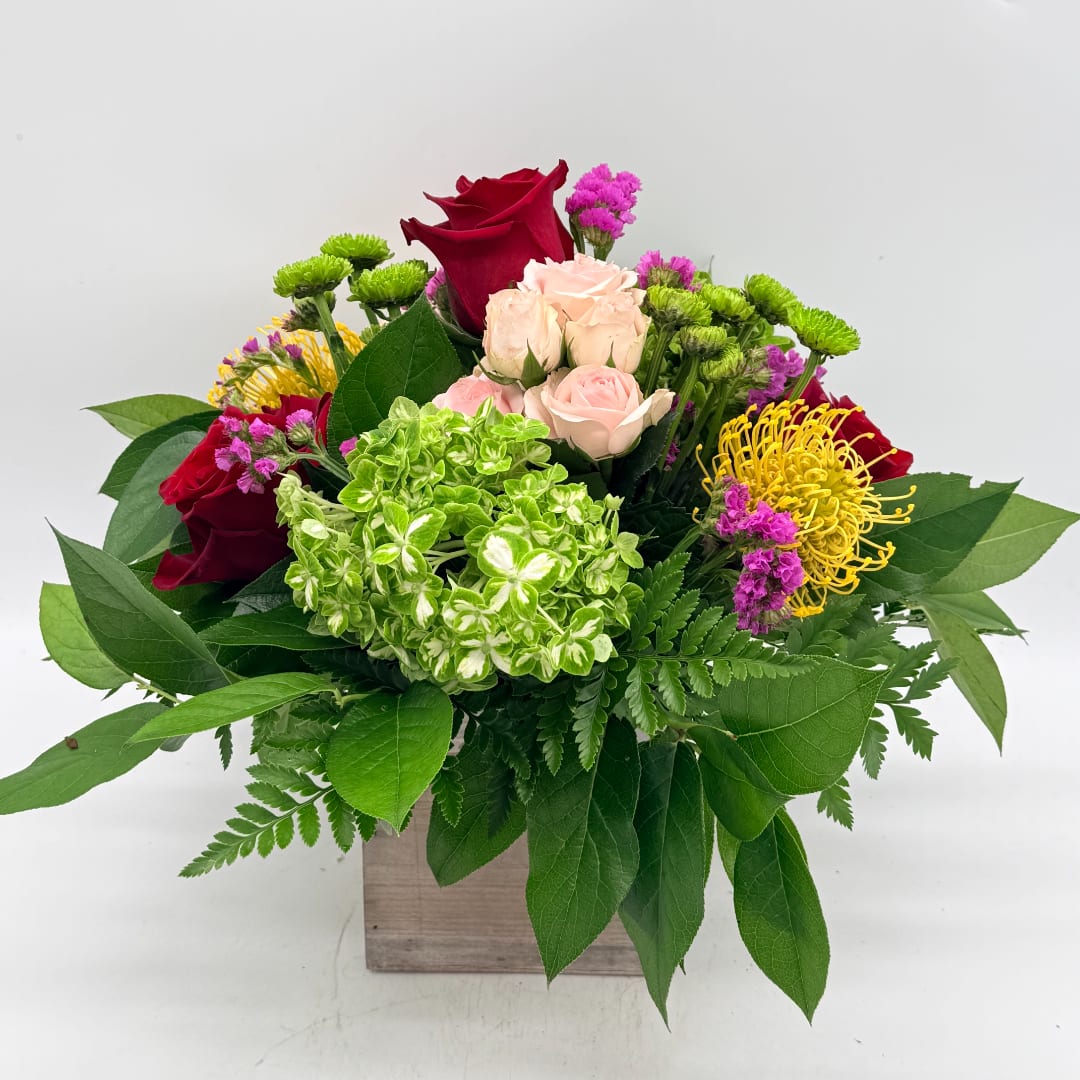 Mixed bouquet of red and blush roses with green hydrangea in a wooden box