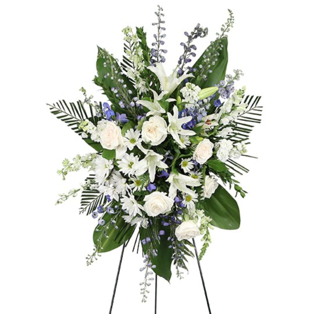 Standing floral spray with white lilies, roses, and blue accents