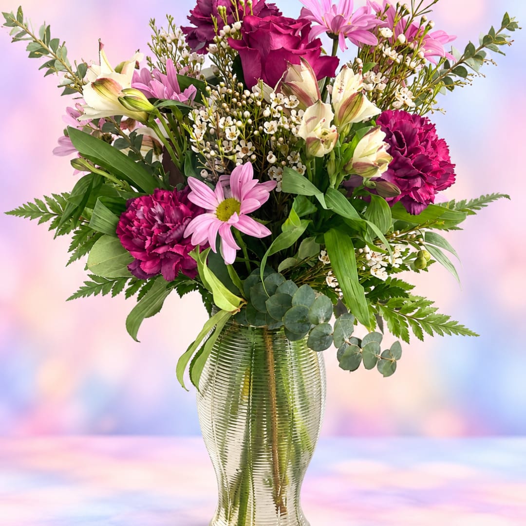 Mixed pink and white flowers arranged in a clear glass vase