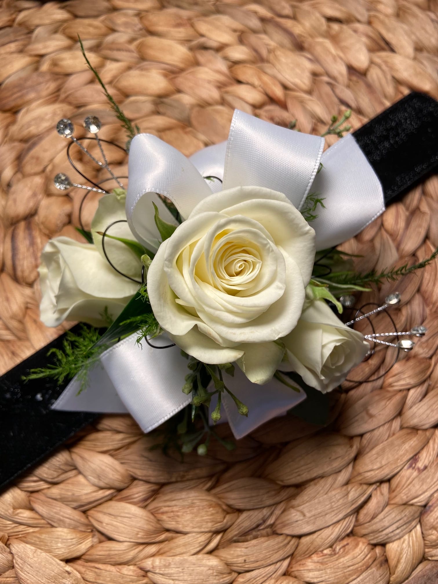 White rose wrist corsage with white ribbon on a black band