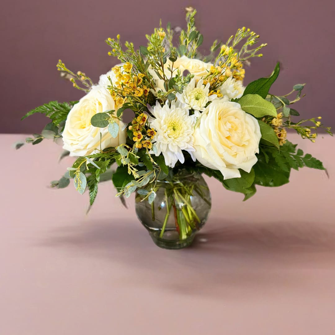 White roses and daisies arranged in a glass vase