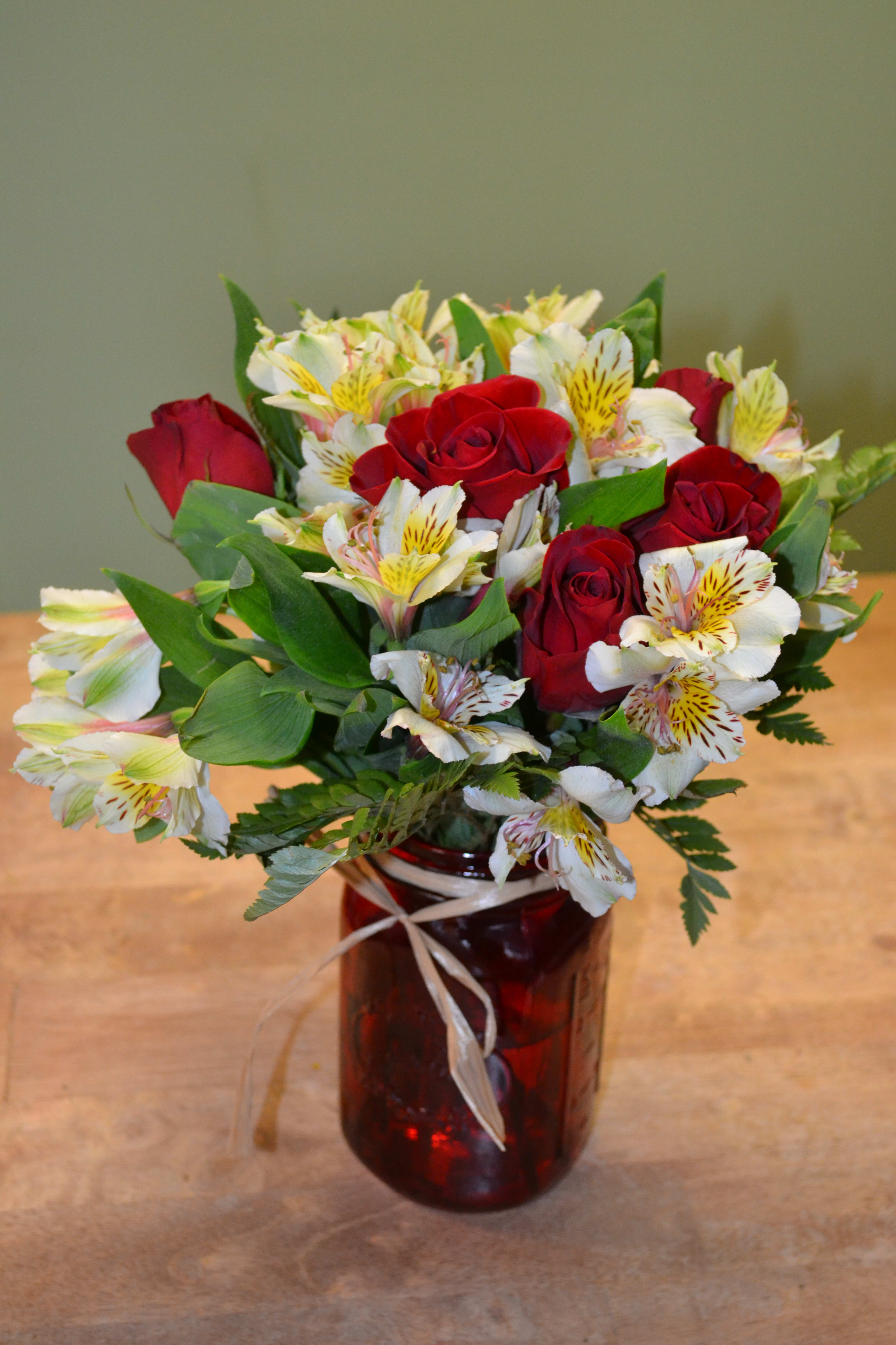 Red roses and white alstroemeria in a red glass vase