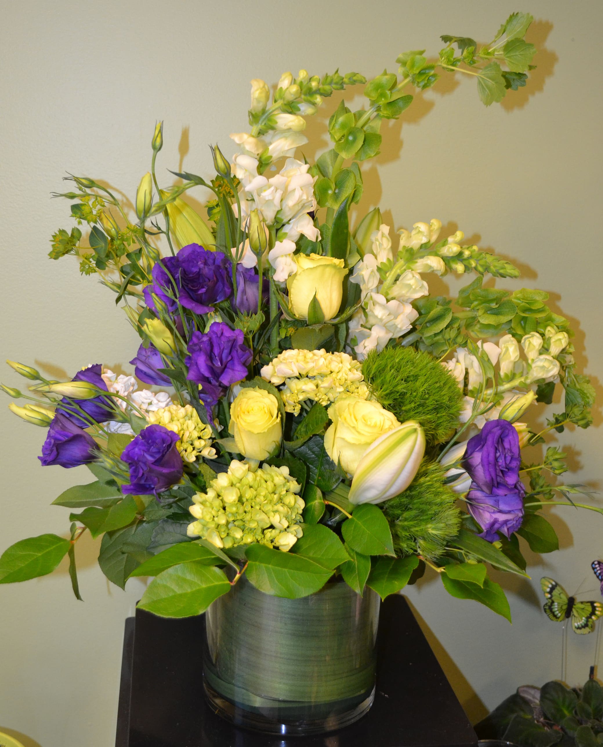 Purple and yellow floral arrangement in a glass vase