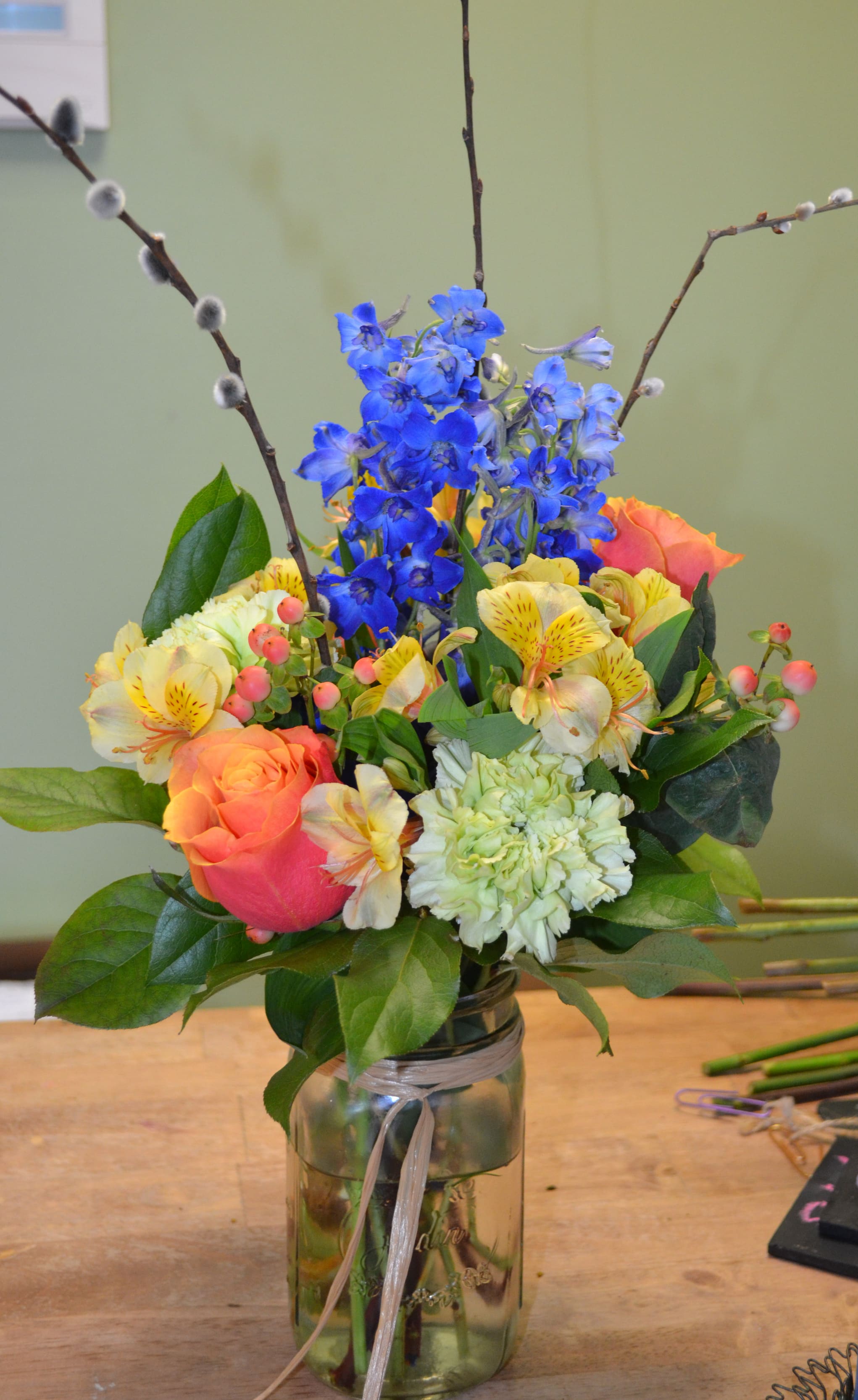 Colorful bouquet in a glass vase with blue flowers and orange roses