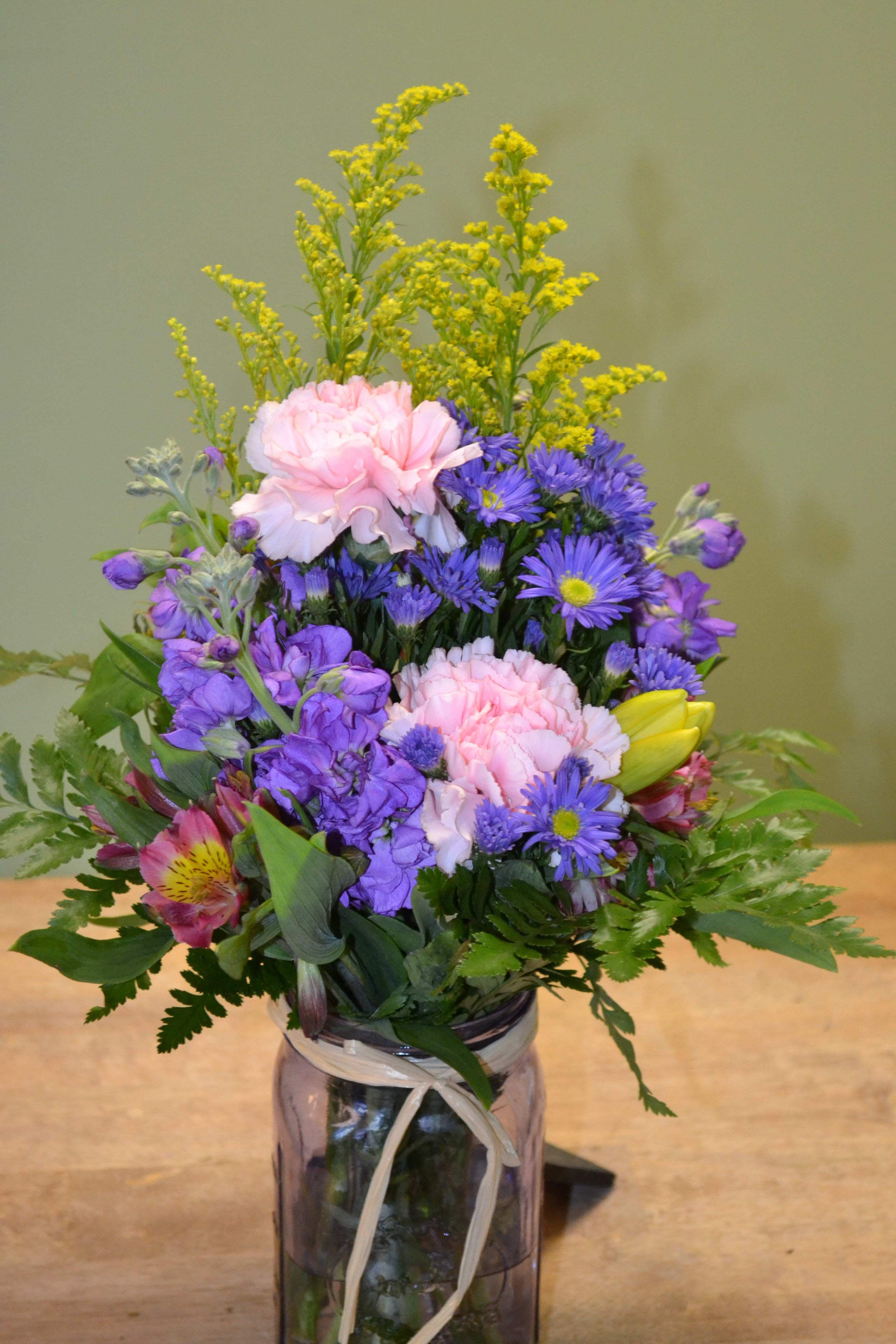 Mixed bouquet in a glass vase with pink, purple, and yellow flowers