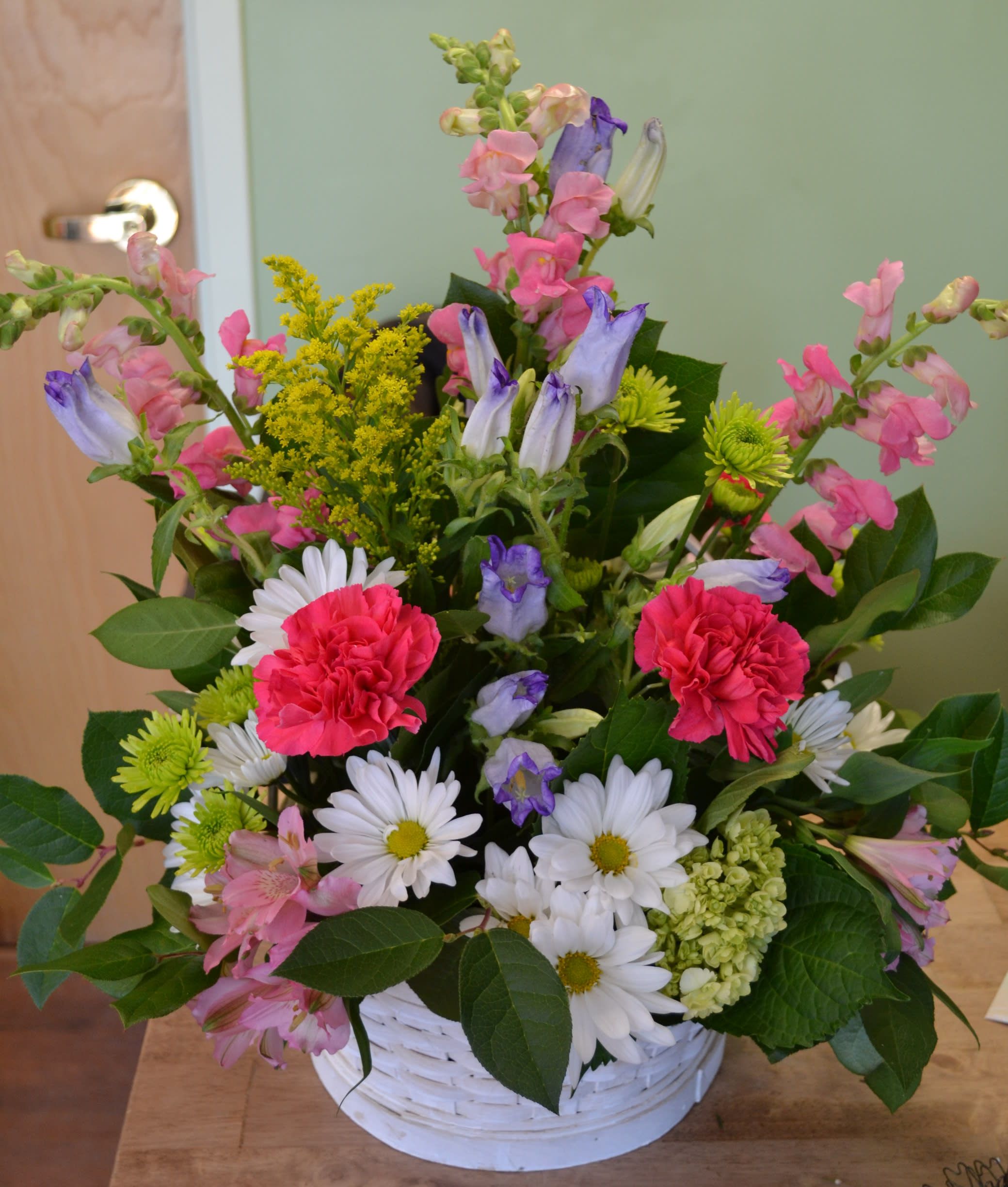 Mixed bouquet in a white basket with pink, purple, and white flowers