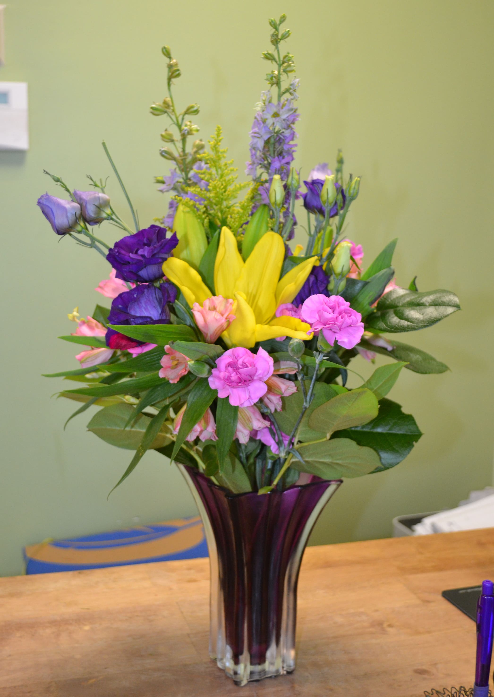 Colorful mixed bouquet in a tall purple glass vase