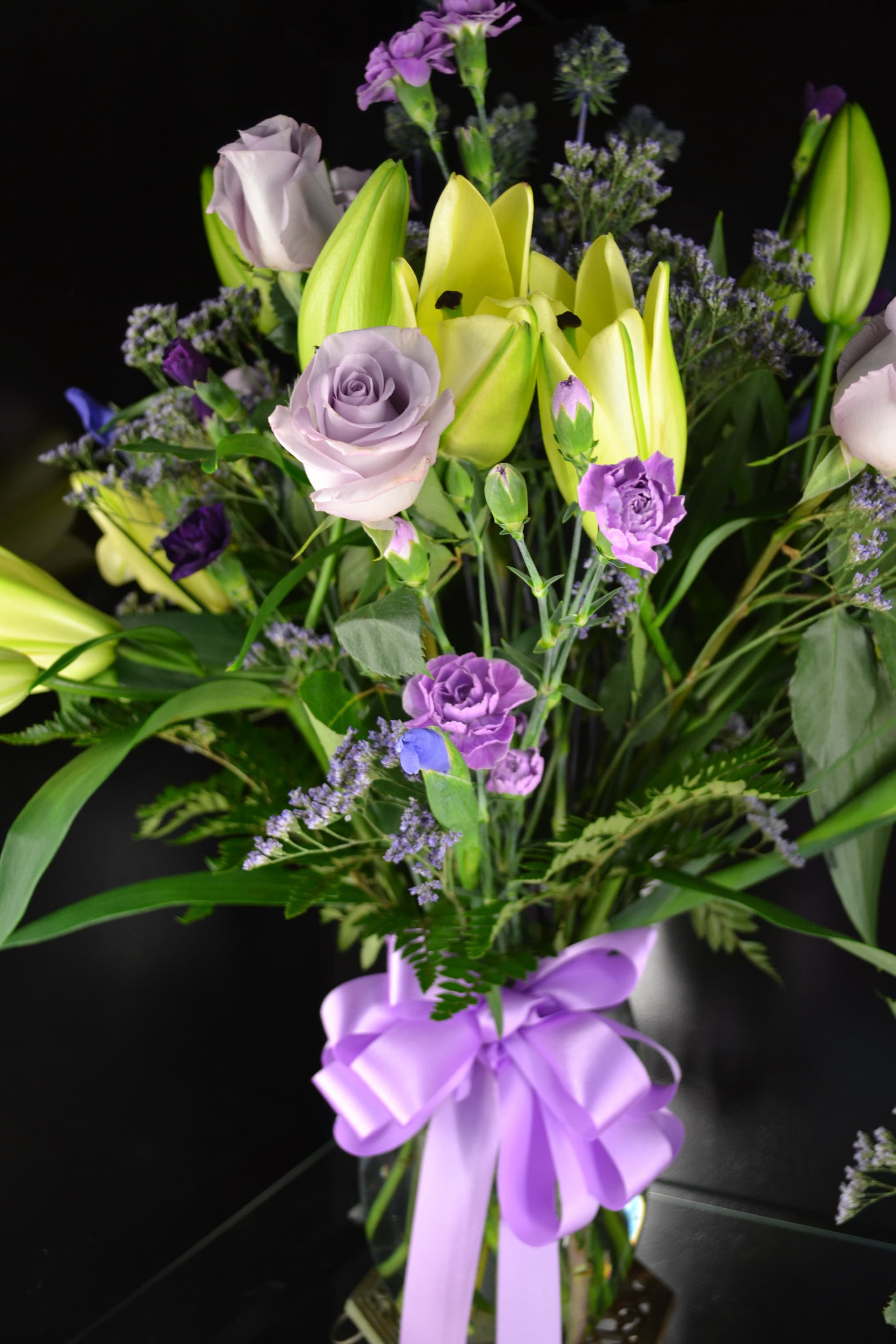 Bouquet of lavender roses and yellow lilies with a purple ribbon