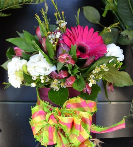 Bouquet of pink gerbera daisies and white flowers with a bright striped ribbon