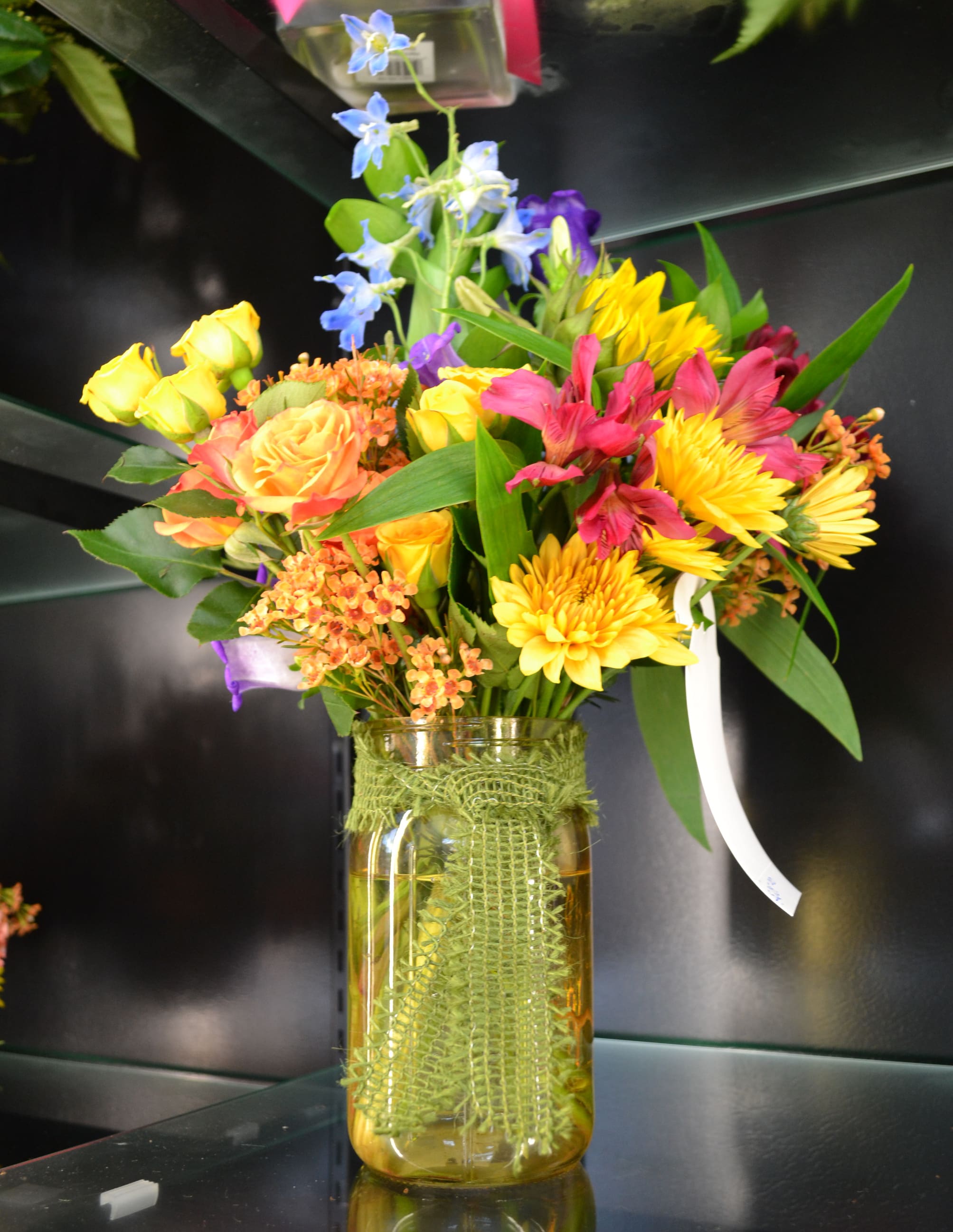Colorful mixed bouquet in a glass vase with yellow, pink, and blue flowers