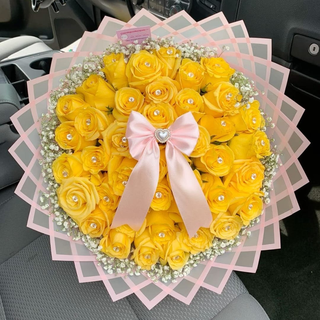 Yellow rose bouquet with a pink ribbon and clear wrap in a car seat