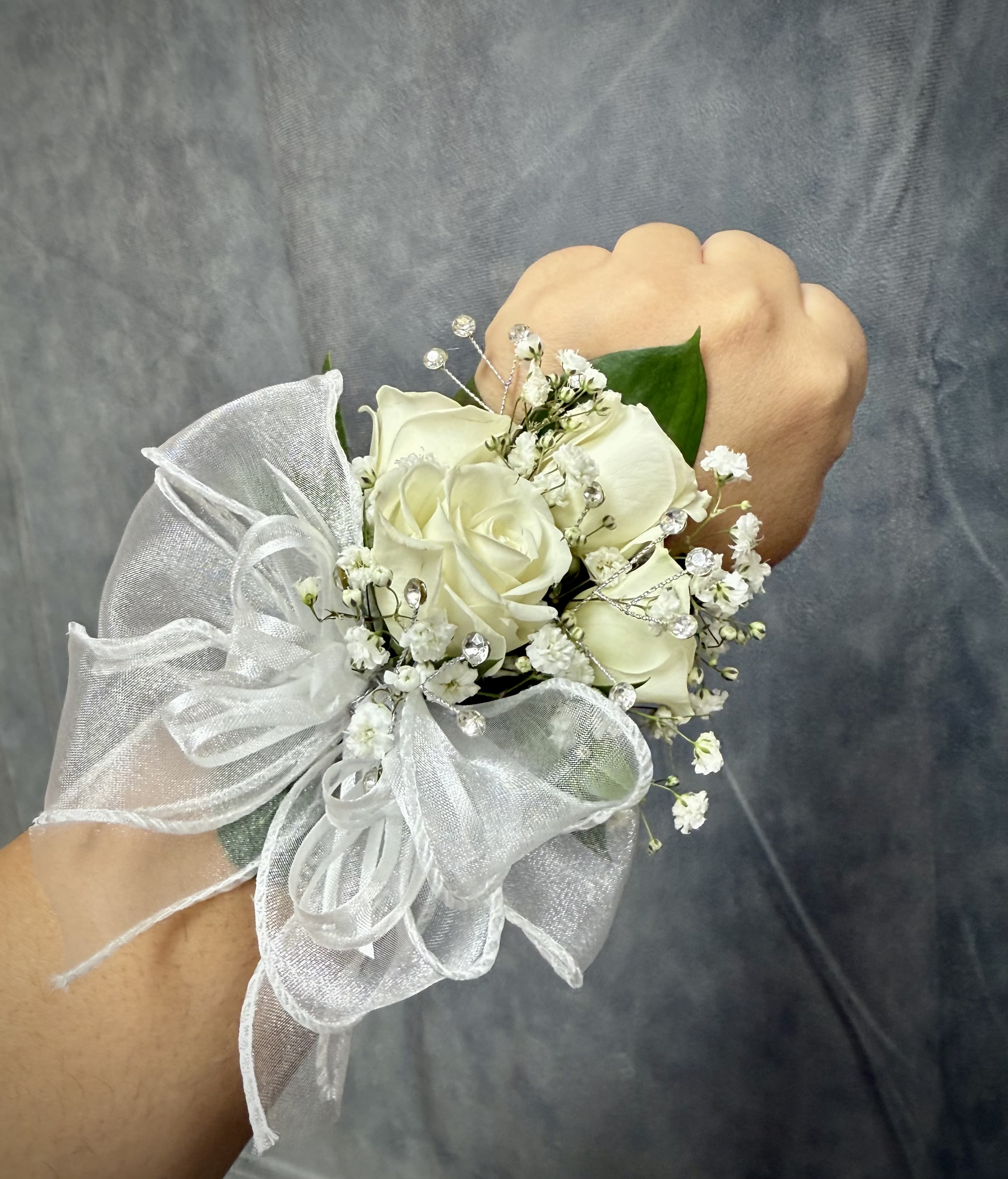 White rose wrist corsage with baby's breath and a sheer ribbon bow