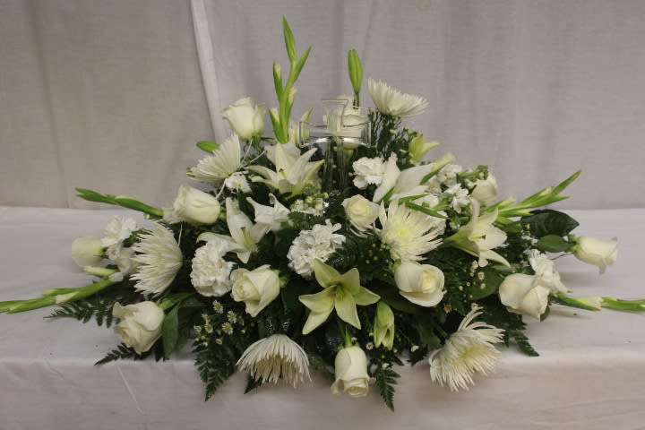 Low white floral centerpiece with roses, lilies, and chrysanthemums