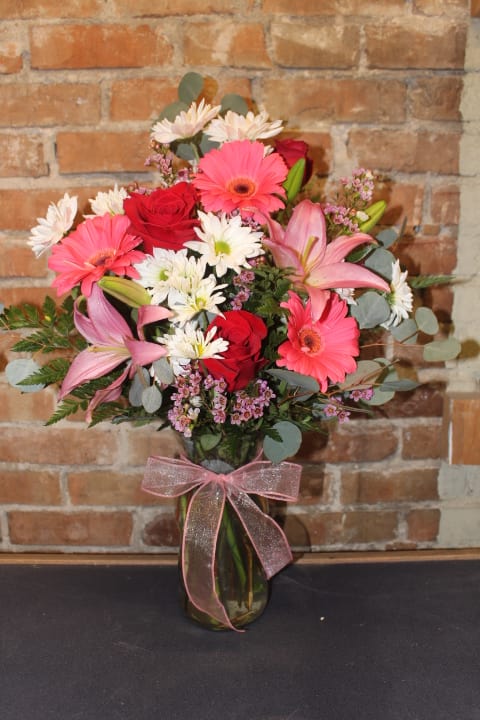 Pink and red mixed bouquet in a glass vase with a ribbon