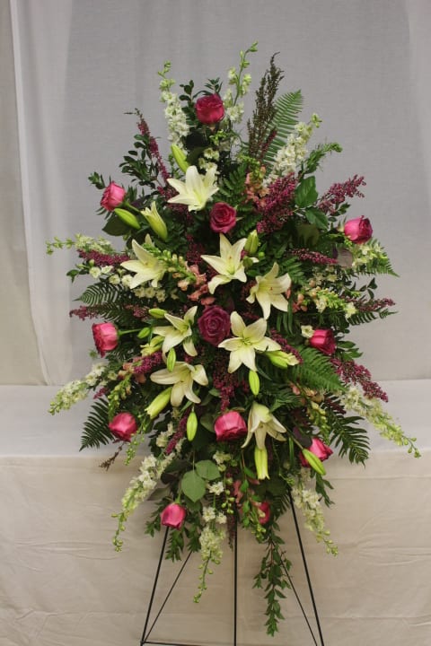 Standing floral spray with pink roses and white lilies on a black easel