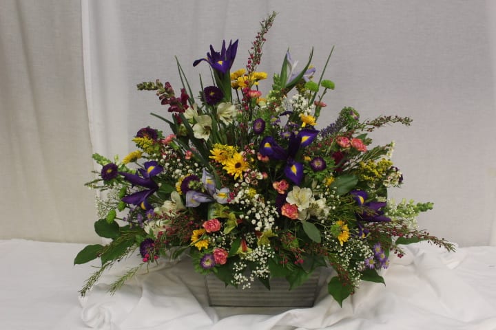 Mixed floral arrangement in a rectangular container with purple, yellow, pink, and white blooms