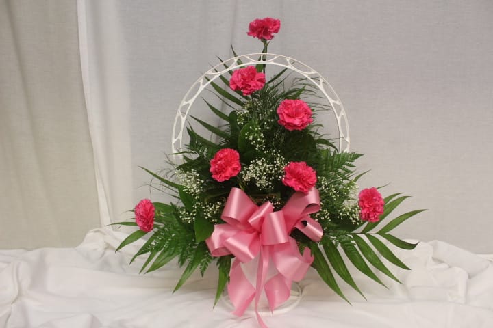 Pink carnations in a white basket with a pink ribbon
