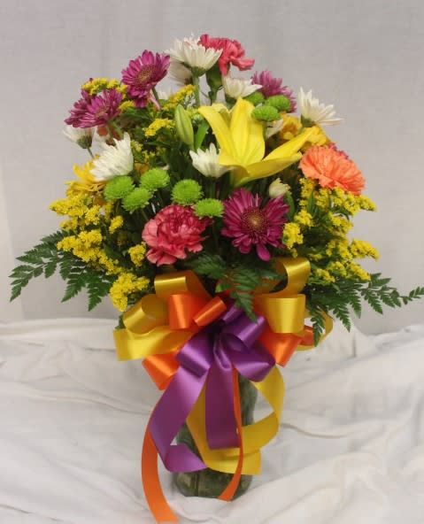 Mixed bouquet in a glass vase with a multicolored ribbon bow