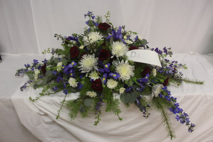 Casket spray with blue, white, and burgundy flowers