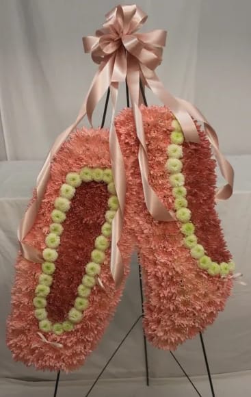Pink floral standing spray with pale ribbon and green accents