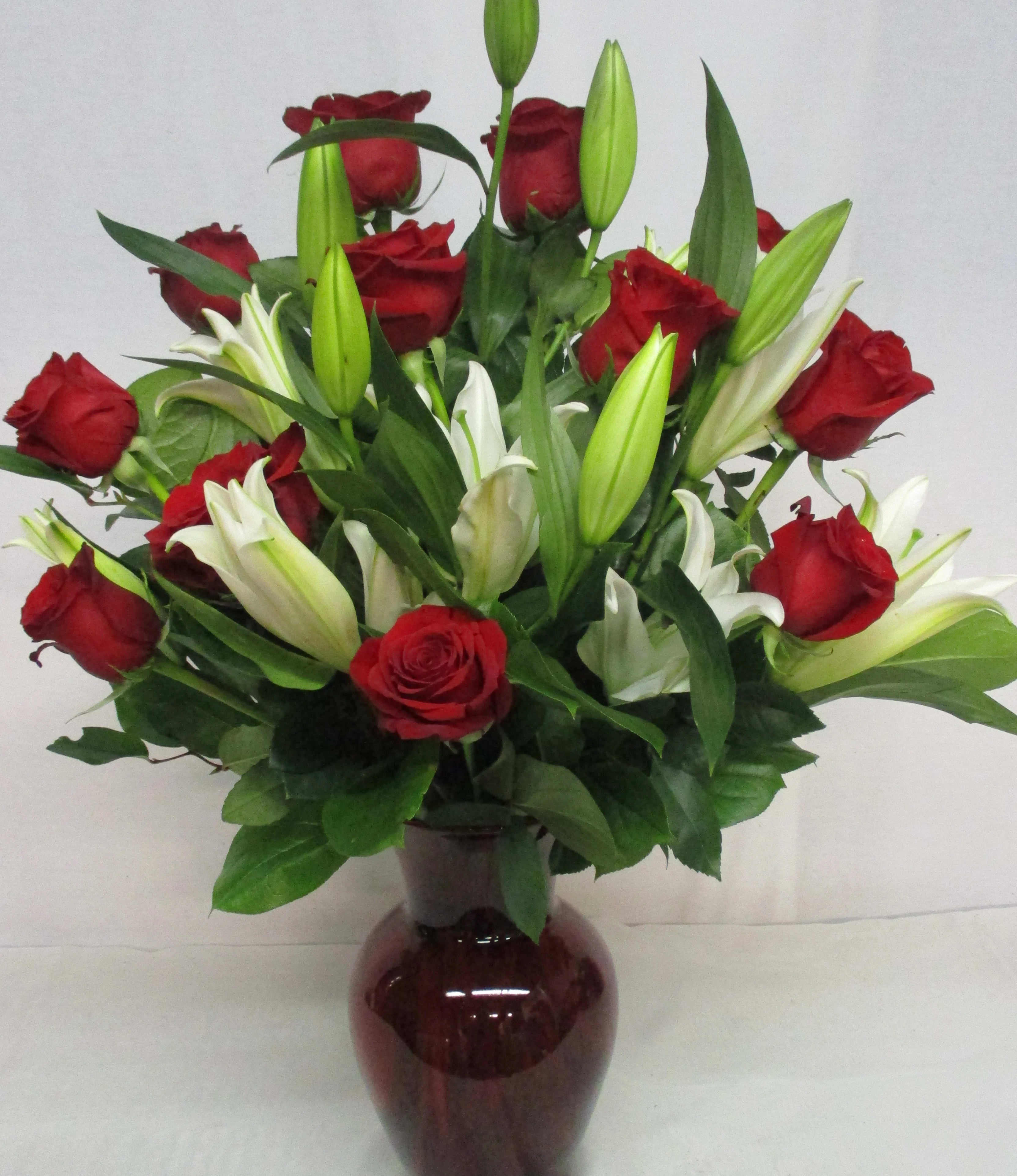 Red roses and white lilies arranged in a dark glass vase